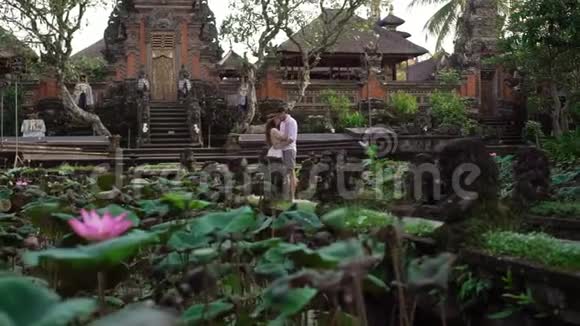 巴厘岛佛寺附近的新婚夫妇牵手拥抱浪漫的婚礼视频的预览图