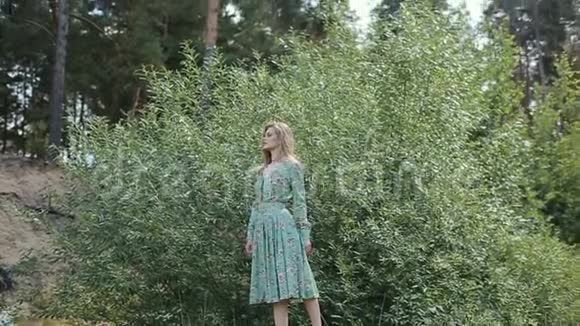 阳光明媚的夏日一个穿着长裙的年轻女孩在公园散步视频的预览图