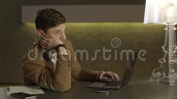 疲倦的商人用他的笔记本电脑完成工作视频的预览图