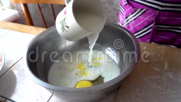 揉面的准备面团的基础把牛奶倒入装有鸡蛋的金属碗中视频的预览图