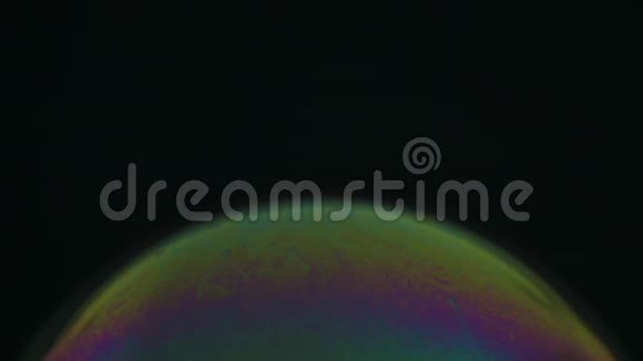 彩虹肥皂泡在黑暗的背景上彩色表面的特写视频的预览图