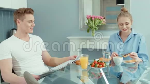 幸福的年轻夫妇在家吃早餐时谈笑风生的肖像视频的预览图