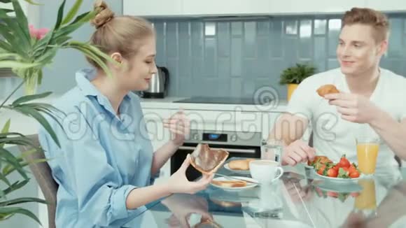幸福的年轻夫妇在家吃早餐时谈笑风生的肖像视频的预览图