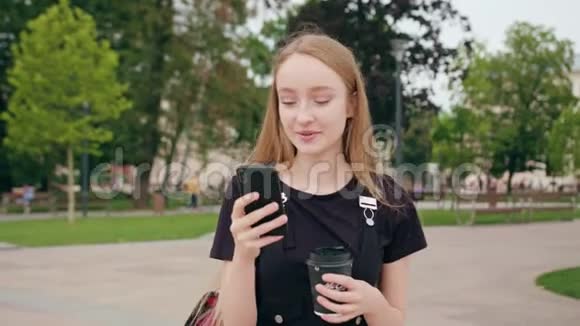 年轻的红头发女士在城里散步和使用电话视频的预览图