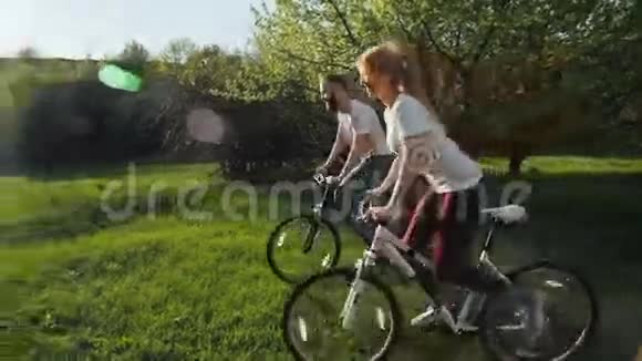 男人和女人在绿色的草地上骑自行车视频的预览图