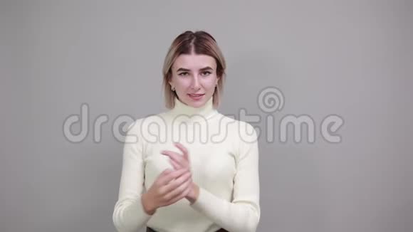 微笑的年轻女子双手交叉隔离在灰色的墙上视频的预览图