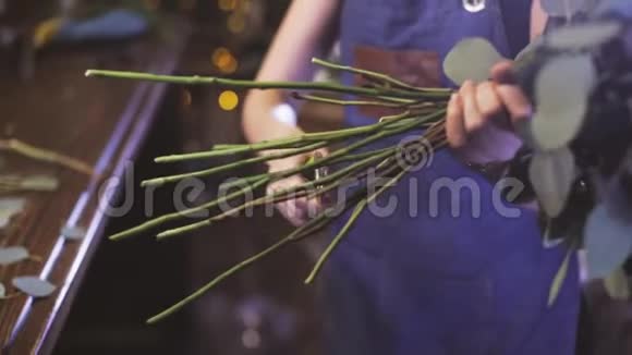 特写镜头年轻的女花匠在花店剪玫瑰视频的预览图
