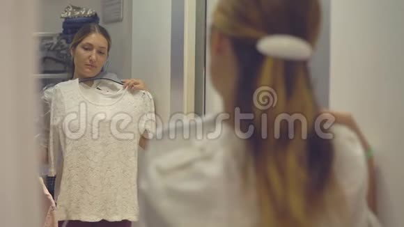漂亮的女孩在购物时在时装店试穿衣服时看着镜子里的倒影视频的预览图