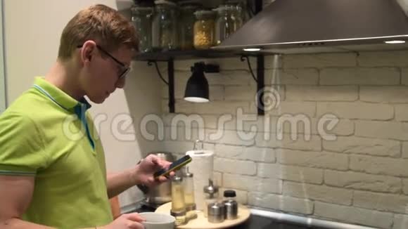 男人在厨房里用手机喝茶视频的预览图