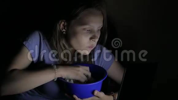 女孩在电影院看电影贪婪地吃着爆米花4UHDK视频的预览图