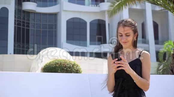 一位年轻女士在酒店附近使用智能手机视频的预览图