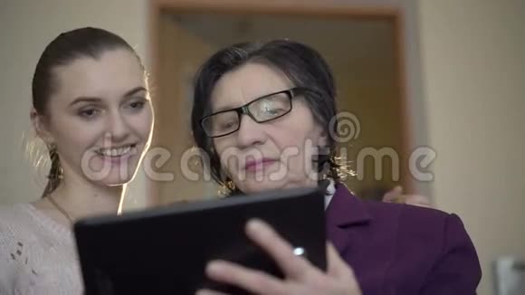 优雅的老商人和年轻女孩在房间背景上使用平板电脑视频的预览图