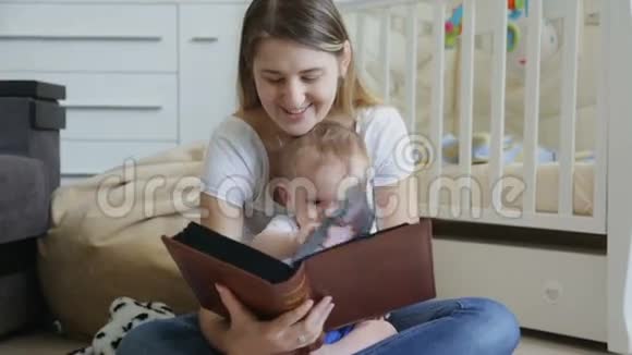 快乐的年轻妈妈带着小男孩在地板上读大书视频的预览图