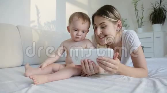 可爱的小男孩使用数字平板电脑母亲在客厅沙发上视频的预览图