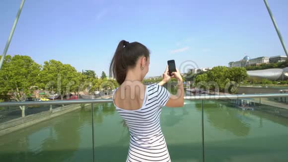 一位年轻的女士在河桥上拍照视频的预览图