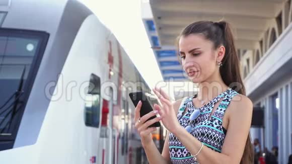 年轻女士在火车站用智能手机视频的预览图