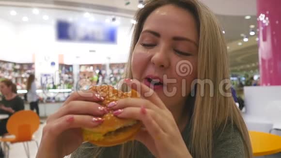 一个特写女孩手里拿着汉堡的肖像年轻迷人的女人吃汉堡包视频的预览图