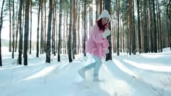 快乐美丽快乐的女孩在树林里的树间奔跑冬天的乐趣调情的年轻女子看着镜头视频的预览图