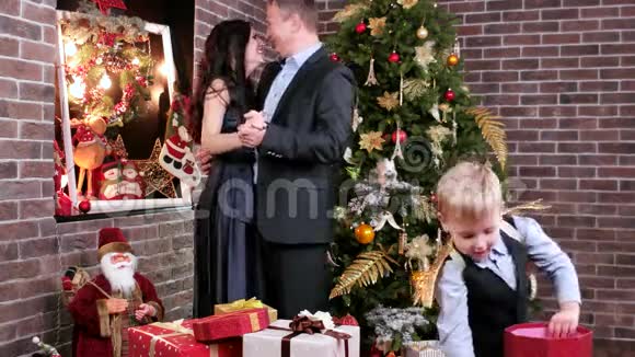 情侣们幸福的父母在圣诞前夕在圣诞树旁的孩子旁边跳舞幸福的家庭视频的预览图
