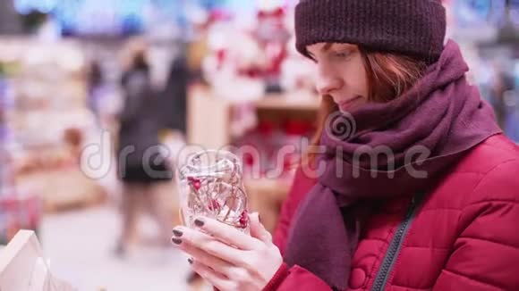 一位年轻的美女在商店里走来走去挑选圣诞装饰品和装饰品来庆祝新年和圣诞节视频的预览图