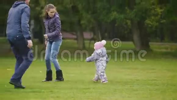 幸福的家庭父亲母亲和小女孩走在秋天的公园里孩子跑着为父母哭泣视频的预览图
