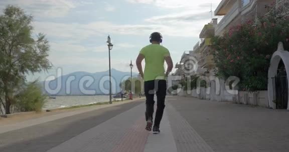 戴耳机的年轻人在希腊佩雷市的公路上奔跑视频的预览图