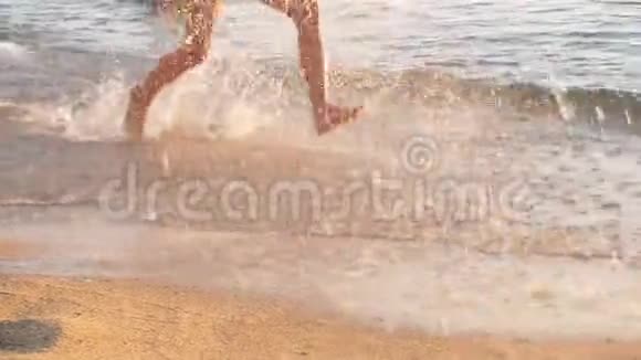 快乐的孩子在日落时在海滩上奔跑举起溅起的水花慢动作视频的预览图