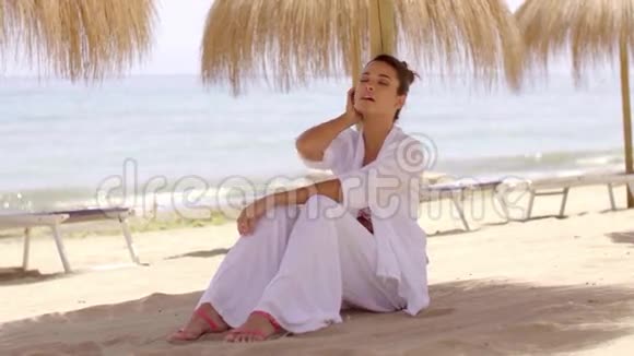 在沙滩上在遮阳伞下放松的女人视频的预览图