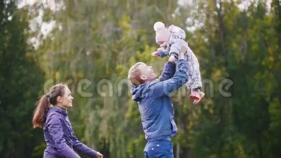 快乐的一家人爸爸妈妈和小女孩走在秋天的公园里爸爸把在怀里慢慢地视频的预览图