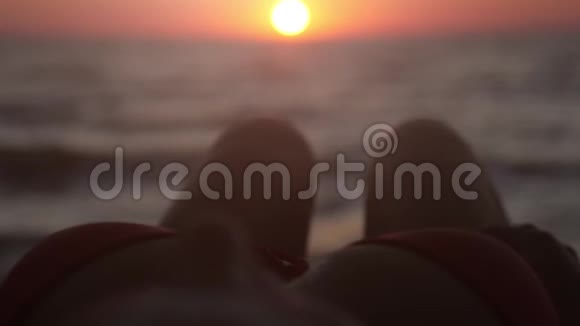 放松的年轻女孩躺在热带海滩上在日落时伸直腿慢动作1920x1080视频的预览图