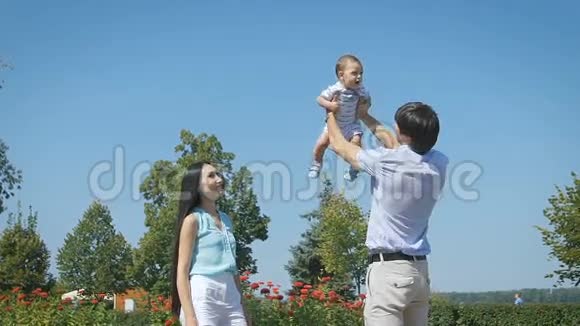 家庭幸福年轻的父亲在天空中抛起婴儿在晴天视频的预览图