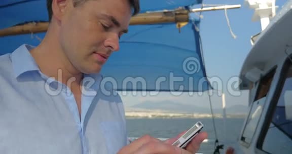 在夏日阳光明媚的天气里当他在船上航行时男人正在打他的智能手机视频的预览图
