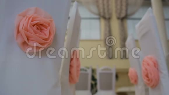 婚礼大厅的内部装饰为客人准备白色椅子上有粉红色玫瑰的漂亮装饰视频的预览图