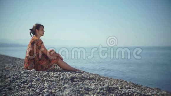 可爱的女孩坐在海滩上心情悲伤视频的预览图