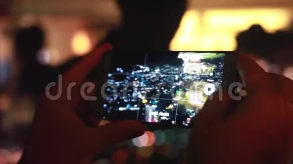 晚上在槟城一座摩天大楼的顶部用智能手机近距离拍摄一栋大楼的顶部视频的预览图
