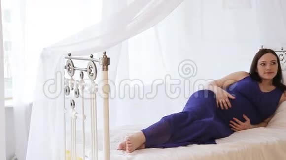 床上穿着蓝色裙子的孕妇视频的预览图