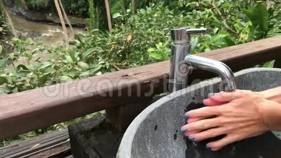女人用美丽的热带景色在外面洗手新鲜度和生态理念巴厘岛视频的预览图