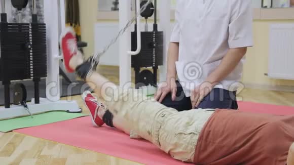 理疗师帮助老年妇女抬腿在健身房做运动健康体操活跃的人视频的预览图