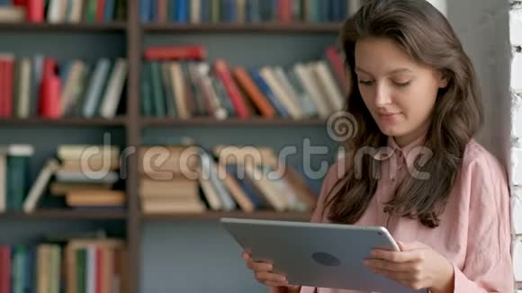 可爱的学生在图书馆里用平板电脑视频的预览图