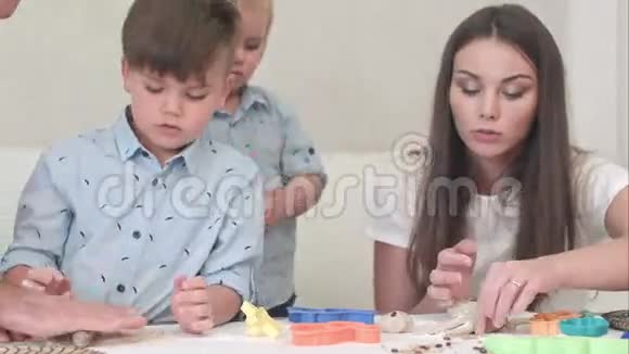 年轻快乐的父母教孩子们如何做饼干视频的预览图