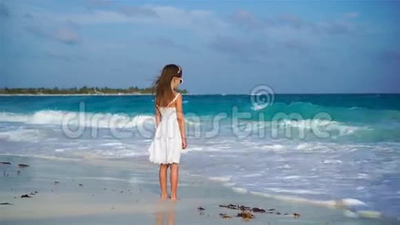 可爱的快乐小女孩在白色海滩上看着海洋喧闹的大海和可爱的小男孩视频的预览图