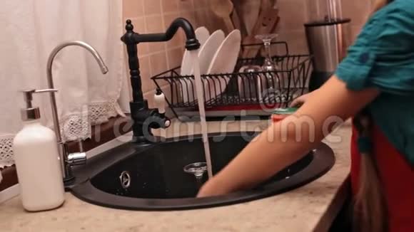 小女孩在厨房洗手池里洗盘子视频的预览图