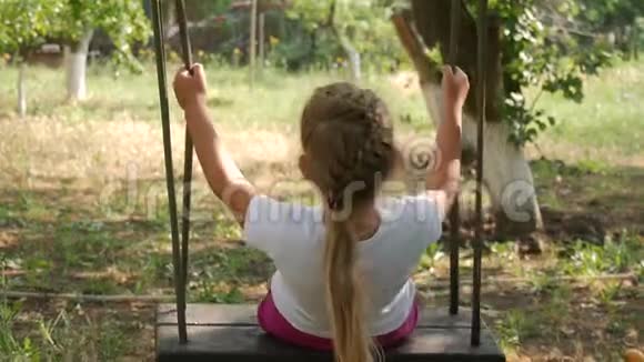 快乐可爱的小女孩在大自然的秋千上摇摆视频的预览图