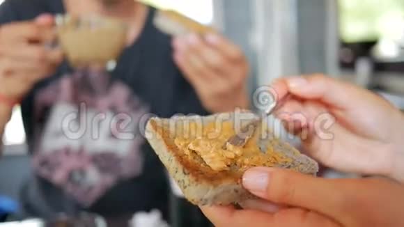 女人手把花生黄油涂在咖啡厅的烤面包上健康早餐高清慢镜头印度尼西亚巴厘视频的预览图