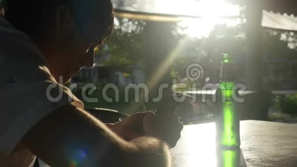 年轻英俊的商人在日落时分在户外咖啡馆喝啤酒有惊人的闪光效果视频的预览图