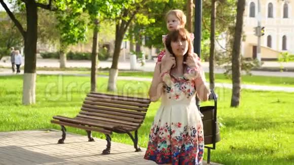 快乐妈妈把小女儿扛在肩上带着孩子在公园散步视频的预览图