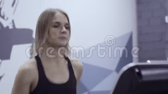 年轻运动的女人在健身房跑步机上跑步视频的预览图