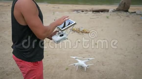 人控制飞行四重机通过遥控平板电脑小屏幕无人机在海滩上起飞高清视频的预览图