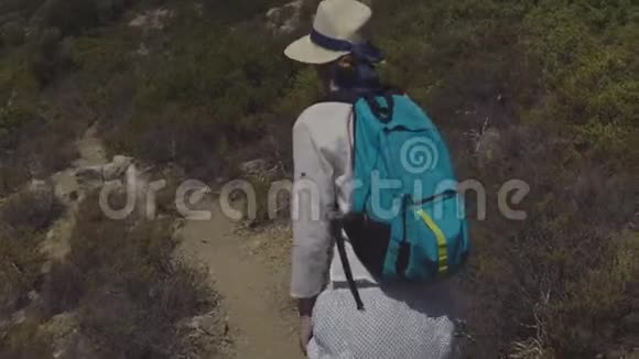 年轻的旅游女孩戴着帽子背着背包微笑着在美丽的大自然中沿着小径散步视频的预览图