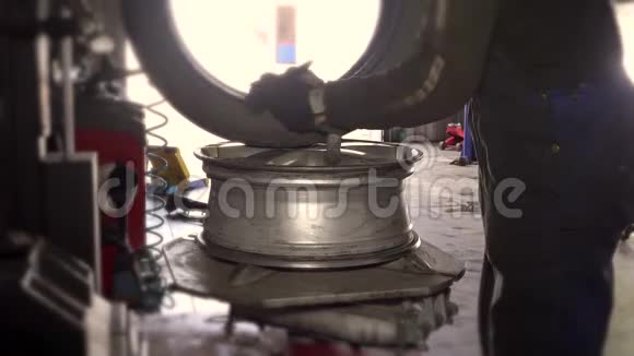 机械师在肮脏的工作中穿着安装轮胎在车轮轮辋上视频的预览图